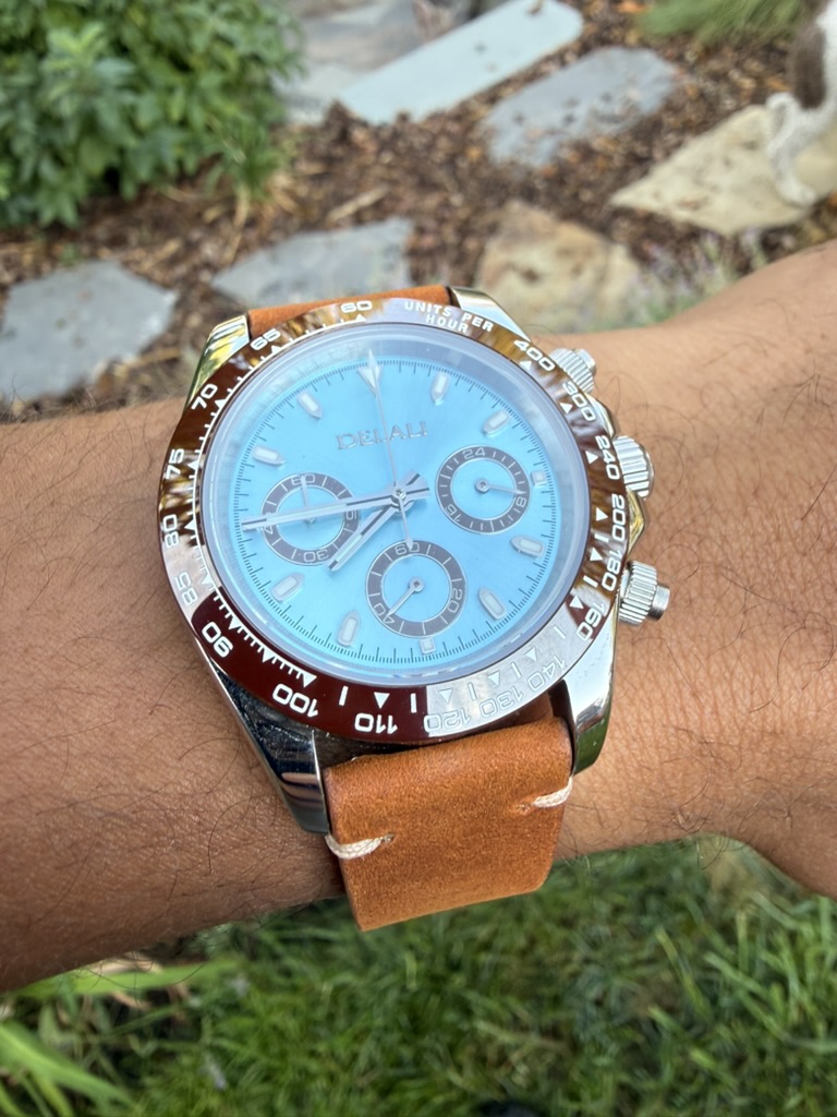 Amber Chronograph Homage — worn on the wrist outdoors on a stone path