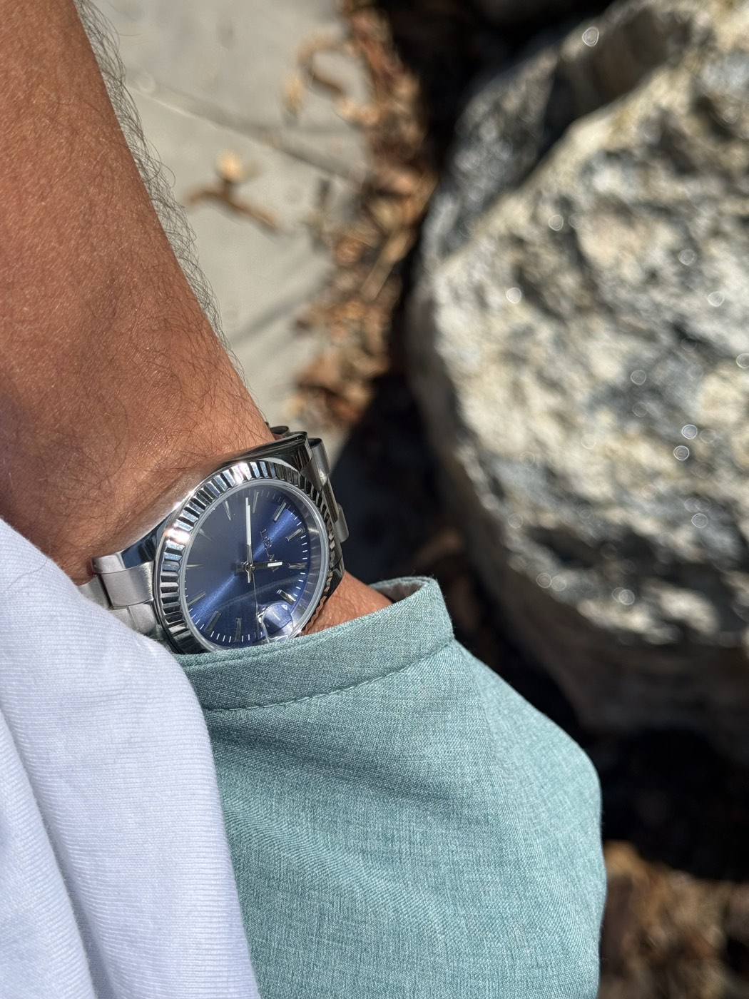 Blue Sunburst Dial Homage — worn on the wrist against granite in bright sunlight